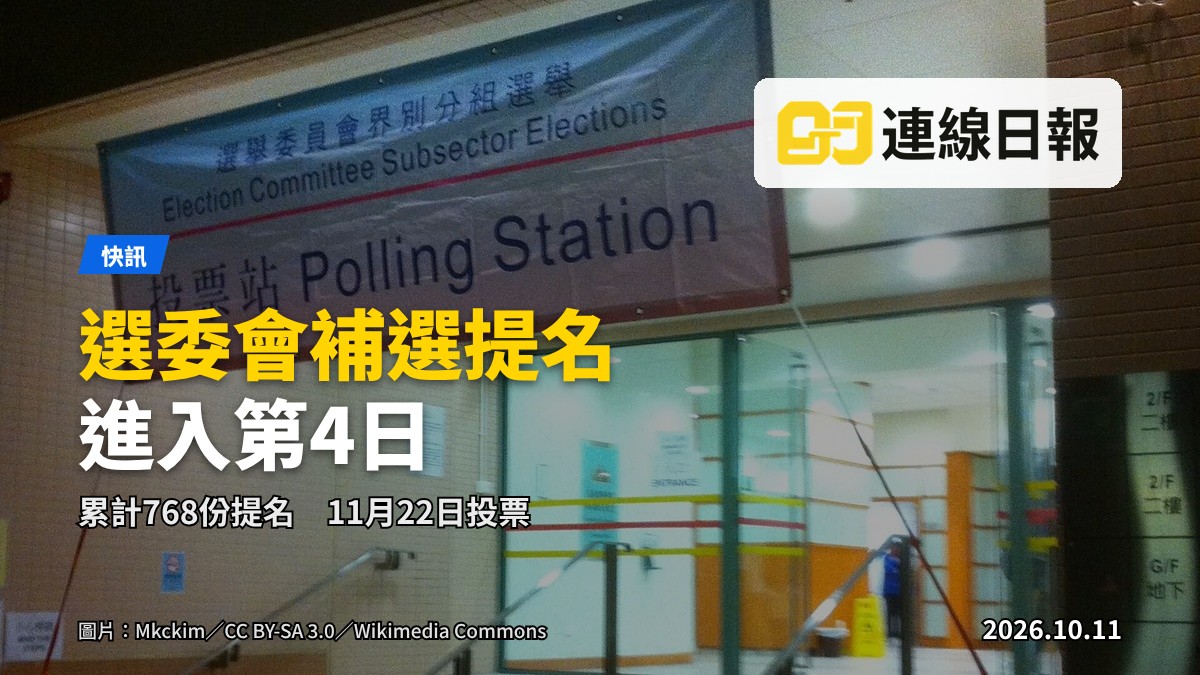 投票站內部，票箱擺在桌上，背景有模糊的選民排隊