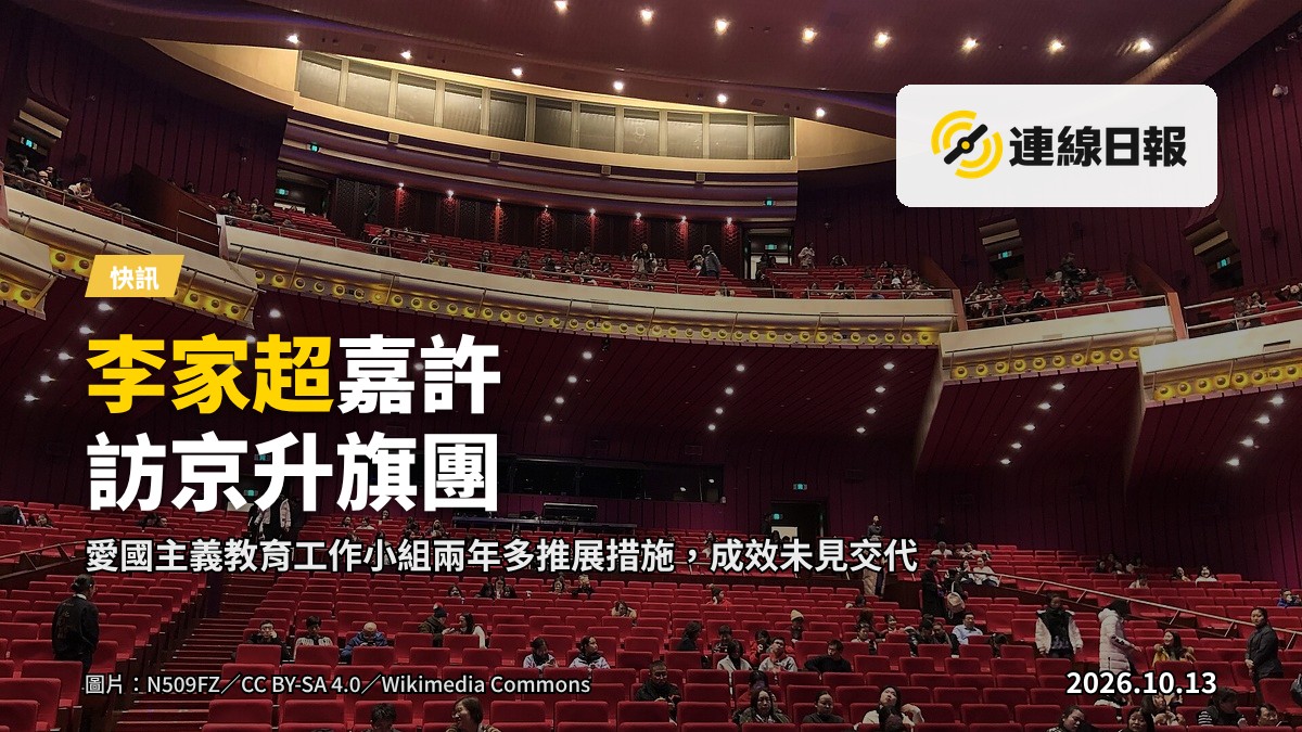 北京禮堂內，學生面對國旗，遠景背影，無可辨識面孔。