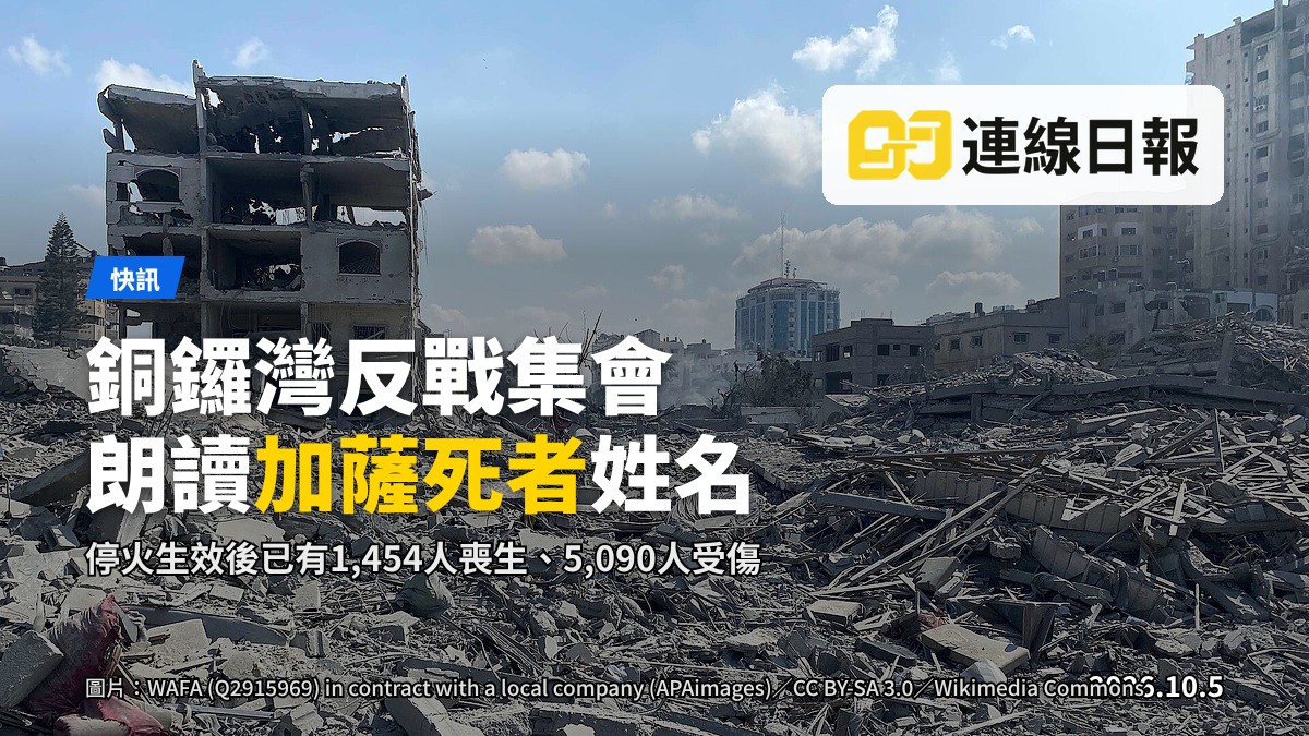 銅鑼灣街頭一個反戰集會攤位，一名活動人士背對鏡頭在白板上書寫，背景人流模糊。